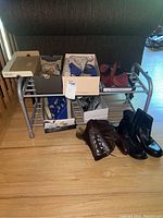 Shoe rack holding multiple pairs of women's shoes with some shoes on floor in front of rack, showing the overall lot contents.