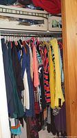 Clothing rack with assorted women's dresses and tops including striped, floral, and solid colors in various fabrics.