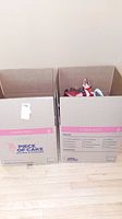 Two cardboard boxes labeled 'Piece of Cake Movers & Storage' filled with women's shoes.
