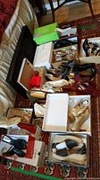 Overview photo showing multiple pairs of women's dress shoes arranged on the floor, including boxes and loose shoes in various colors and styles.