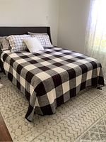 Full view of bed with buffalo plaid bedspread and pillows showing the color and pattern of the items.