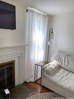 Curtains hung in living room area near fireplace, showing light filtering through