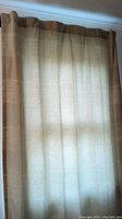 Curtain hanging showing wheat and light grey fabric with light filtering through.