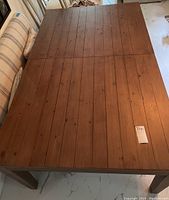 Top-down view of rectangular plank-style wood table top showing wood grain and lot tag.