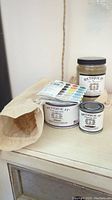 Clear wax jar with brushes and color test chart on a white surface