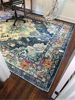 View of large multi-color area rug in an office setting with floral and abstract patterns and a wood floor.