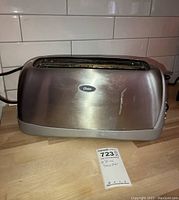 Front view of Oster four-slice toaster showing stainless steel body and Oster logo on front.