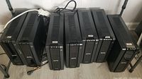 Seven APC UPS 1500 units lined up, some plugged in, showing varied screen states and physical wear.