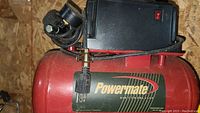 Close-up of red Powermate air compressor with attached gauge and black control box on top.