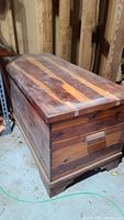 View of vintage cedar chest showing striped wood tones on lid and surface wear.