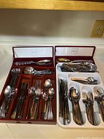 Two trays of mixed flatware including forks, knives, spoons, with Mikasa salad serving set in a box above
