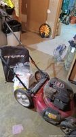 Full view of red Murray lawn mower with black Briggs and Stratton engine cover and attached grass collection bag.