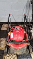 Front view of red Troy-Bilt push lawn mower showing engine cover and cutting deck