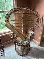 Full view of peacock chair leaning near window with two bamboo shades on seat