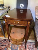 Front view of the rectangular drop leaf table showing drawer and decorative inlay on legs.