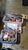 Three plastic containers filled with various tools including a hand saw, chisels, and multiple accessory bits and discs.