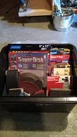 Black tote filled with sandpaper sheets, sanding discs, and sanding blocks