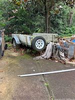 Side view of galvanized trailer body showing spare tire mounted on side and moss growth on panels