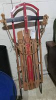 Front view of vintage Paris Champion sled showing red metal frame, wood slats with branding, and attached rope.