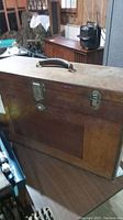 Front view of wooden toolbox showing latch hardware and leather handle