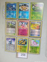Photo showing 9 Pokemon holographic trading cards laid out in 3x3 grid. Each card features a different Pokemon character, with holographic shine visible on some cards.