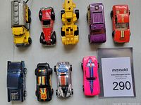Top-down view of nine vintage die cast Hot Wheels cars showing various models and colors.