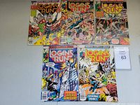 Top down view of five Logan's Run comics #1-4 and #7 on table showing front covers with Marvel Comics Group banner and 30 cent price.