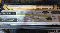 Photo showing two boxed 24-inch strip fluorescent lights, one Kitchen & Bath F20 tube, and the other a generic 24-inch strip light fixture.