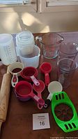 Photo showing wooden rolling pin, multiple measuring cups and spoons in various materials and colors, and measuring pitchers.