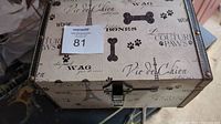 Closed view of dog-themed storage box with lock on front and dog-related design printed on exterior surfaces.