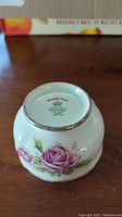 Bottom of a fine bone china creamer marked Royal Standard Orleans Rose with a pink rose design and gold trim.