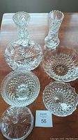 Seven crystal items including various bowls and vases arranged on table showing overall lot contents.