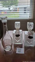Three decanters on a table in front of a window highlighting their clarity and patterns.