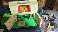Barn playset with open doors showing animal figures inside and fenced area