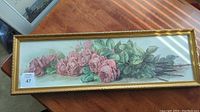 Frontal view of the floral wall art showing pink roses and green leaves in horizontal orientation inside a gold-colored frame.