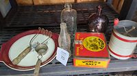 Overview of all vintage kitchen items including bottles, plate, tobacco tin, tools, and canister