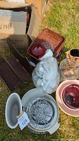Photo showing white ceramic pie plates, white and red bowls, metal wire rack, wicker tea light basket, wooden trays, and a bag with white balls.