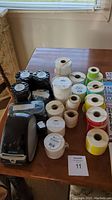 Photo showing Dymo label maker and multiple rolls of label tape in various colors and sizes on a table