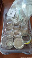 View of eight Mason jars with metal lids in plastic basket, showing jars and lids from above.