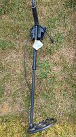 Metal detector laid out on grass showing full length from search coil to handle and armrest