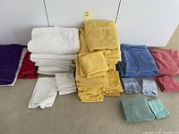 Photo showing assorted colorful bath linens grouped by size and color including white, yellow, blue, red, purple, green, and pink towels and washcloths.