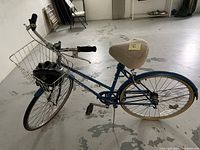 Blue Eurotour three-speed bicycle with visible padded seat, black helmet in front basket, and pedals.