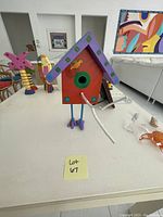 Front view of colorful wooden birdhouse with painted details and metal legs