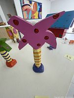 Photo showing large purple wooden palm tree with red swirls, striped trunk, and blue base