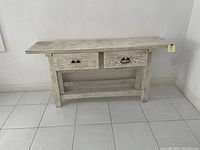 Photo of the full wooden entry/sofa table showing distressed white paint, two front drawers with different black metal pulls and an open lower shelf