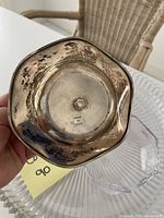 Bottom of metal pedestal bowl showing tarnished silver-tone finish and sticker reading 'Made in India'.