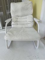 Front view of the cushioned patio chair showing white metal frame and beige cushions with lumbar support cushion.