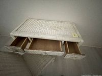 White wicker desk from top showing three open drawers, surface, and drawer interiors.