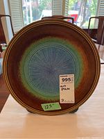 Front view of decorative ceramic art plate showing radial center pattern and gradient brown to blue-green glaze
