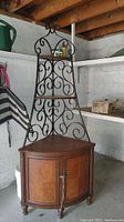 Full view of corner cabinet showing wood base with two doors and decorative metal frame with wood shelves